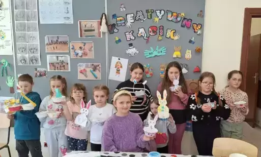 Dzieci trzymają w rękach koszyczki wykonane na zajęciach.